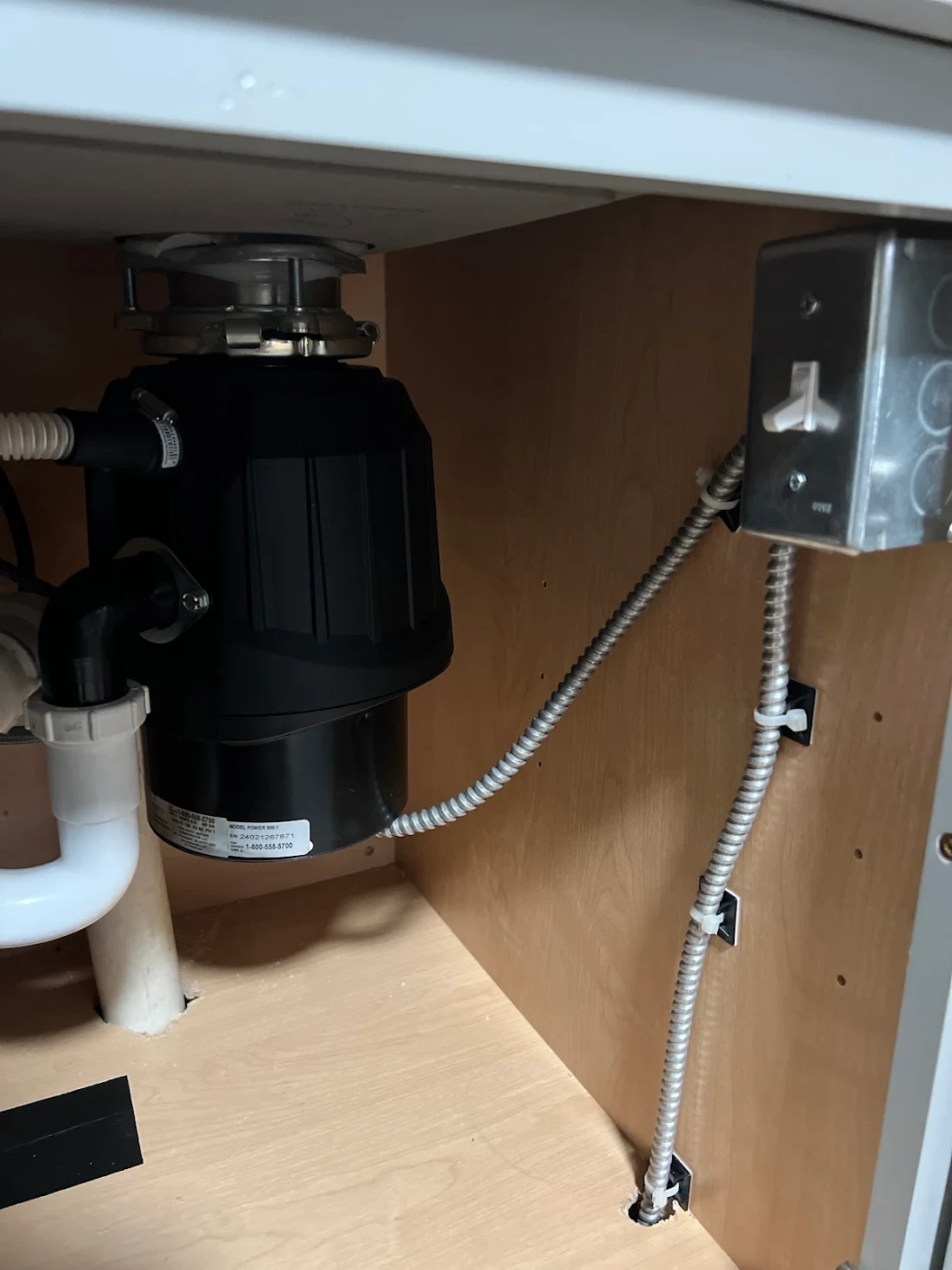 A garbage disposal and wiring installed under a kitchen sink by Graff's