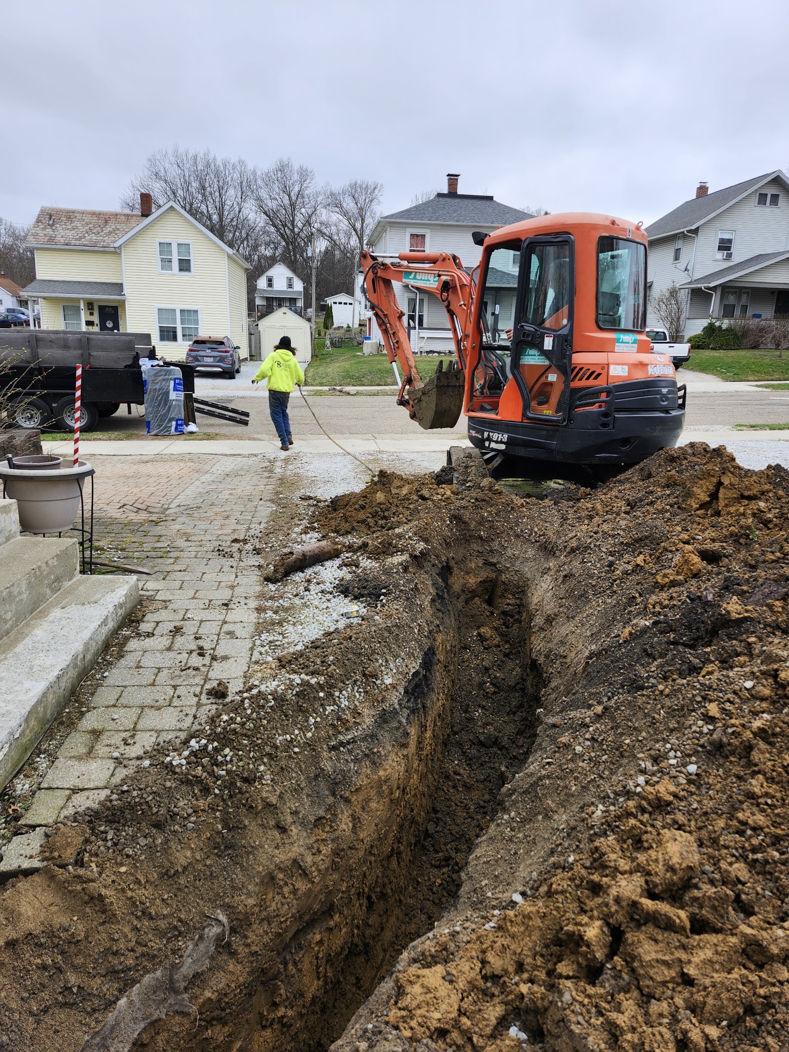 A Graff's crew digging a new water line trench beside a house